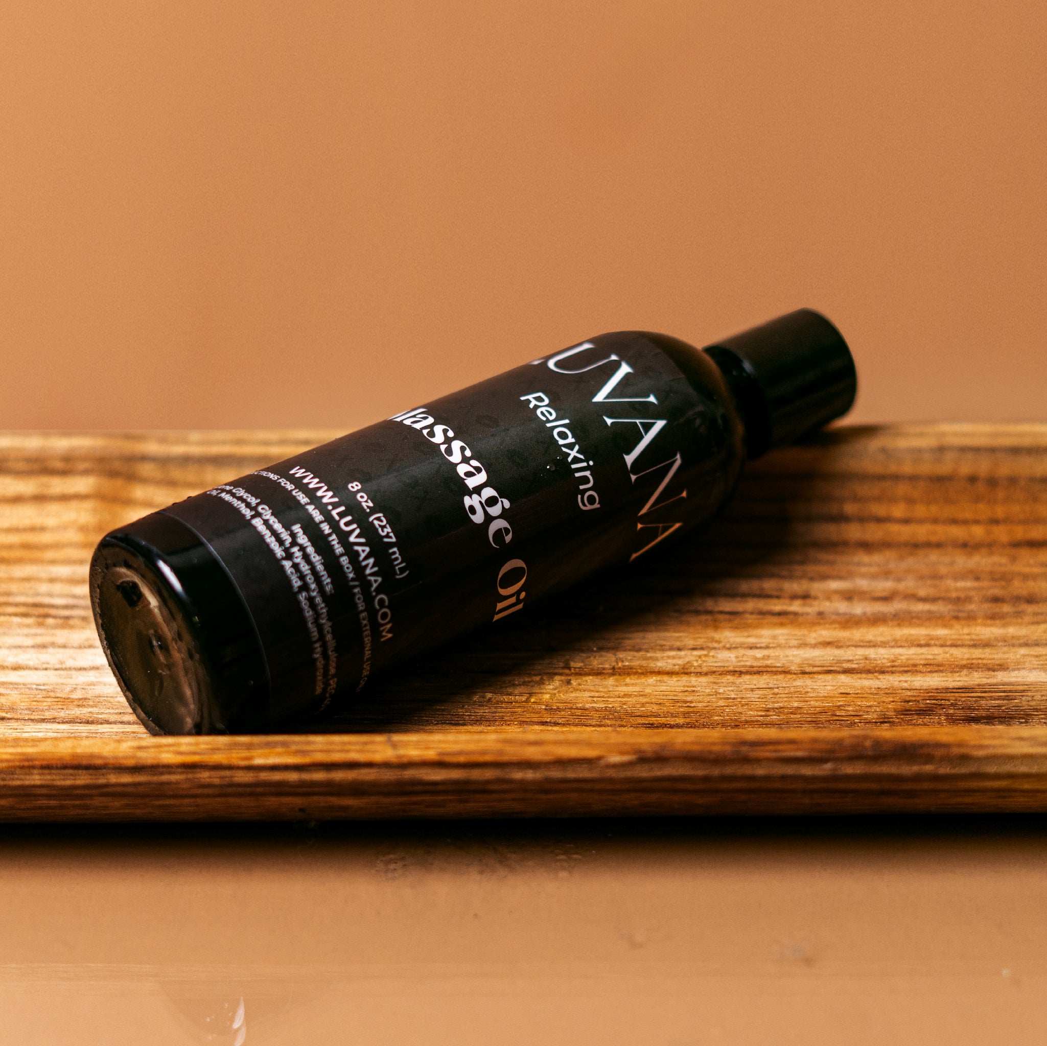 Luvana Lavender Massage Oil bottle on wooden tray with warm background, relaxing massage and body oil made in Puerto Rico.