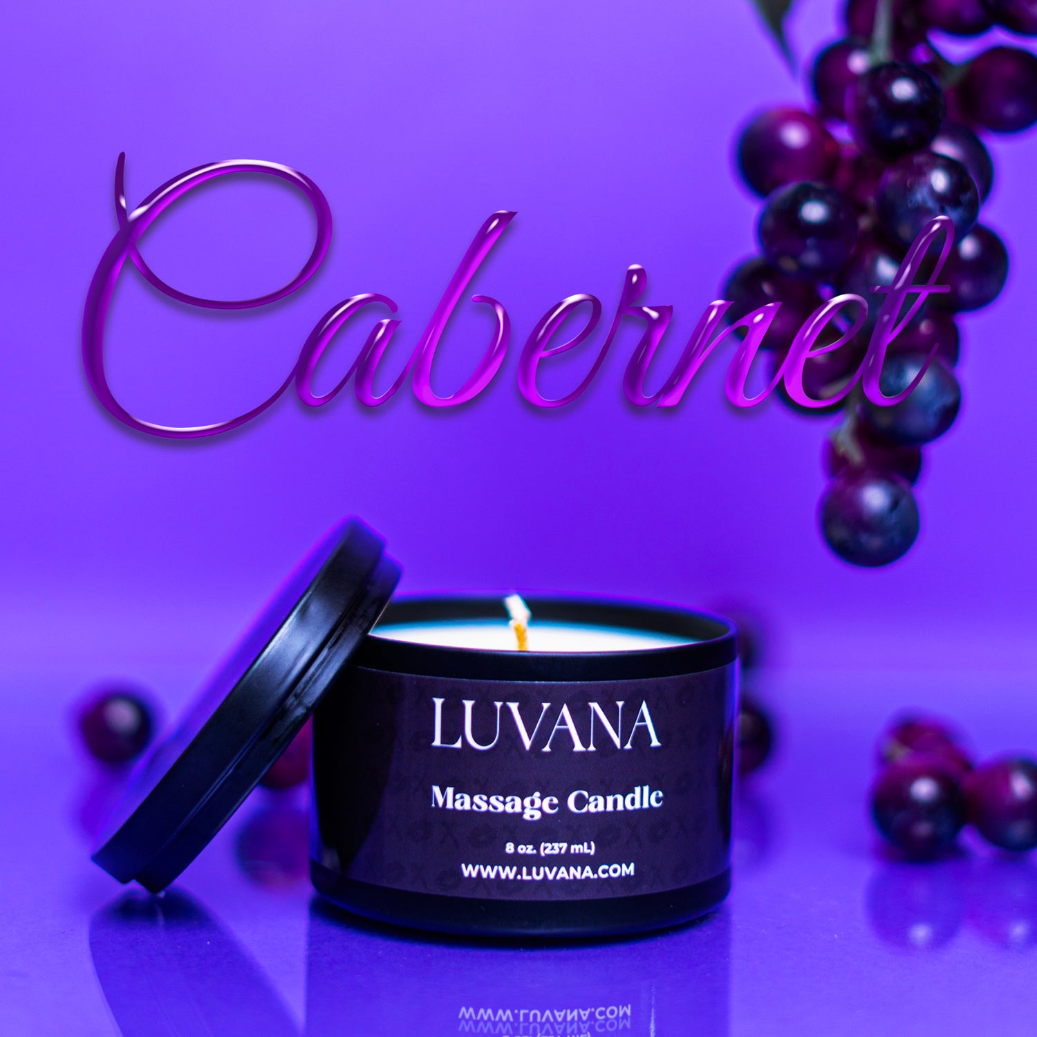 Luvana Massage Candle in Cabernet scent on purple background with grapes, soy wax massage oil candle made in Puerto Rico.