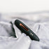 Close-up of Luvana Mini Bliss bullet vibrator resting on soft plush fabric, matte black with rose-gold accent.