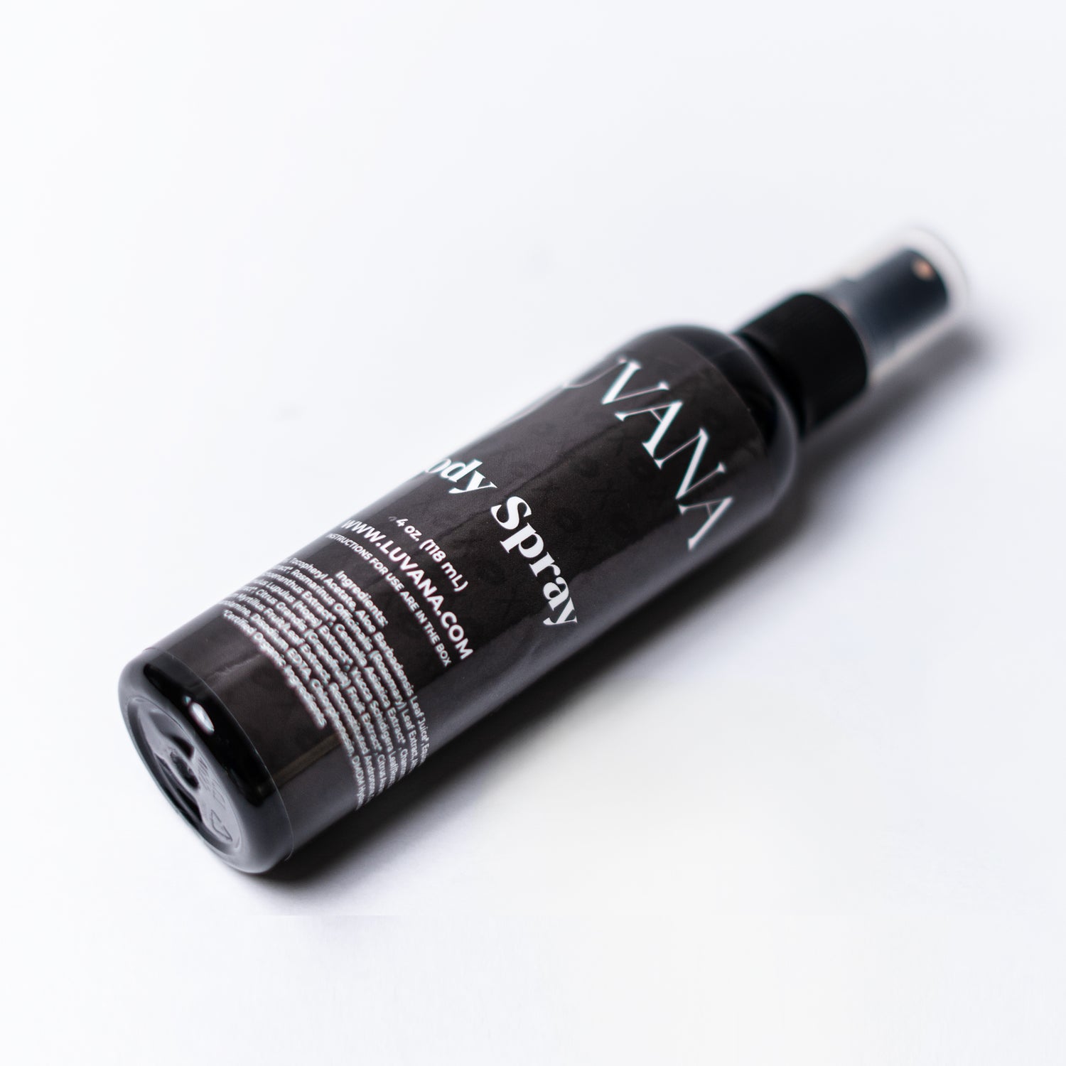 Lifestyle photo of Luvana Cabernet Body Spray being misted on skin for instant hydration and long-lasting fragrance with grape, strawberry, pear, and vanilla notes.