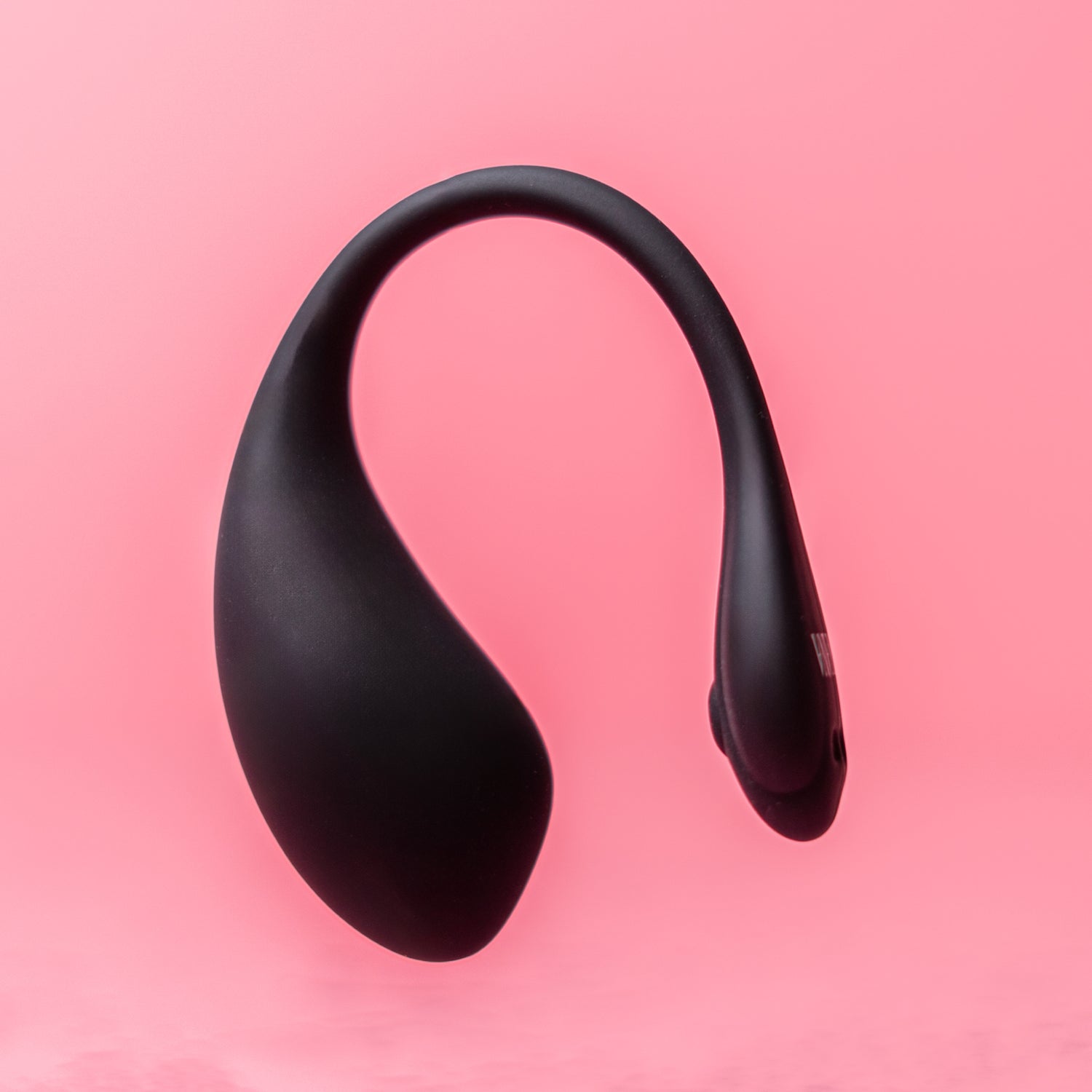 Luvana Duo Bliss black wearable couples vibrator floating product photo on pink background, sleek body-safe silicone design