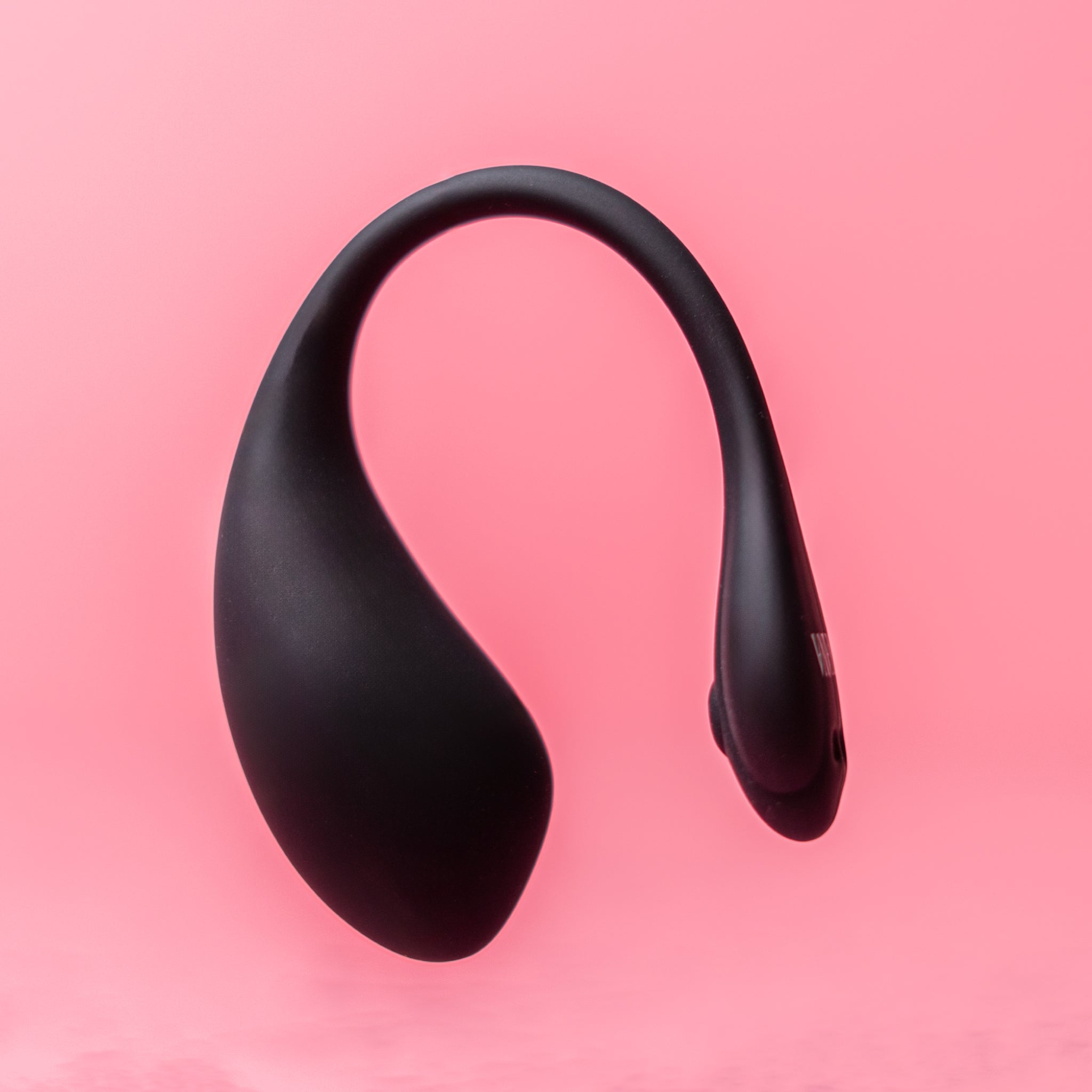 Luvana Duo Bliss black wearable couples vibrator floating product photo on pink background, sleek body-safe silicone design