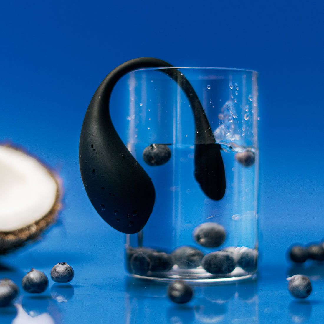 Luvana Duo Bliss waterproof wearable couples vibrator in a glass of water, demonstrating water-resistant design with lifestyle styling