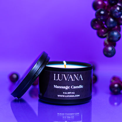 Lit Luvana Massage Candle with lid beside it on purple background with grapes, soy wax massage oil candle made in Puerto Rico.
