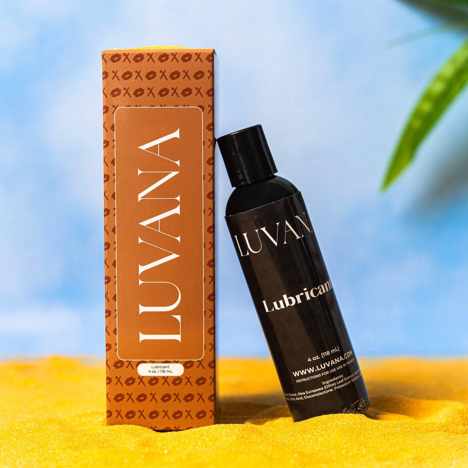 Luvana water-based lubricant 4 oz (118 mL) bottle leaning against Luvana packaging on sand with a blue background and tropical leaves