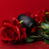 Luvana Obsidian Rose rose-shaped clitoral vibrator in black, product shot with red roses on a red background