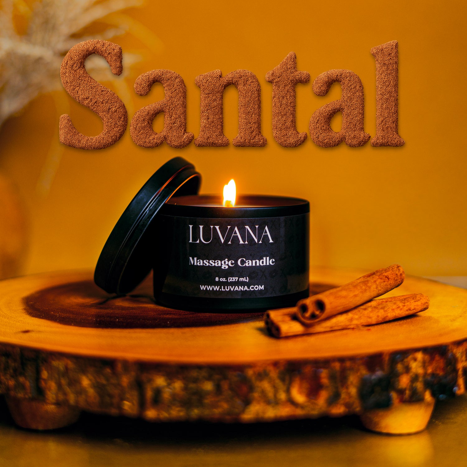 Lit Luvana Massage Candle in Santal scent with lid and cinnamon sticks on wooden tray, soy wax massage oil candle made in Puerto Rico.